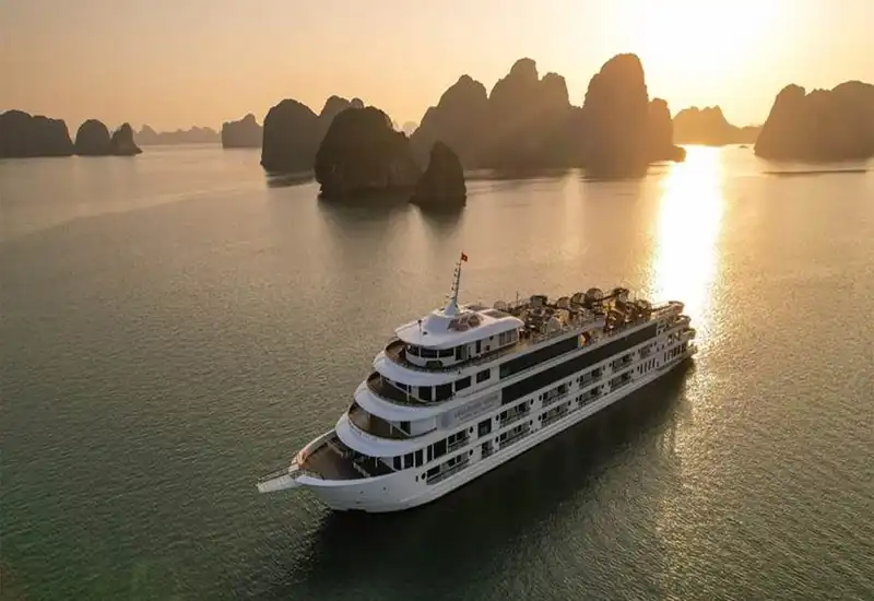 a Cruise sailing under the sunset of Halong Bay
