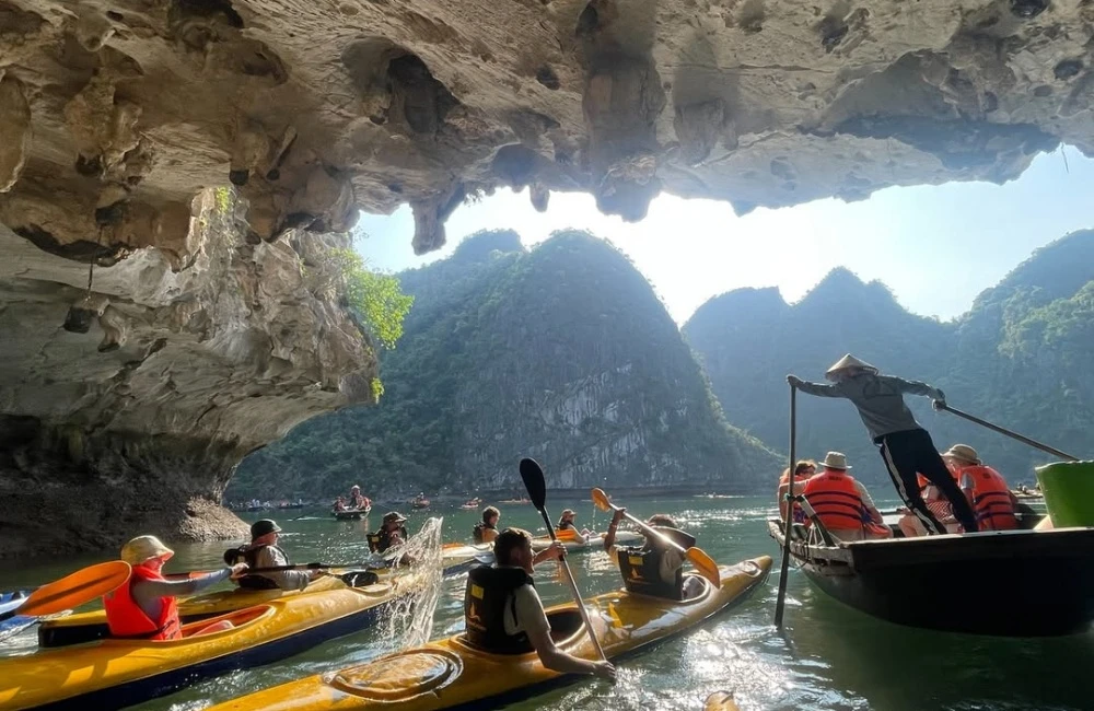 Travelers kayaking under Luon Cave in Halong Bay in August