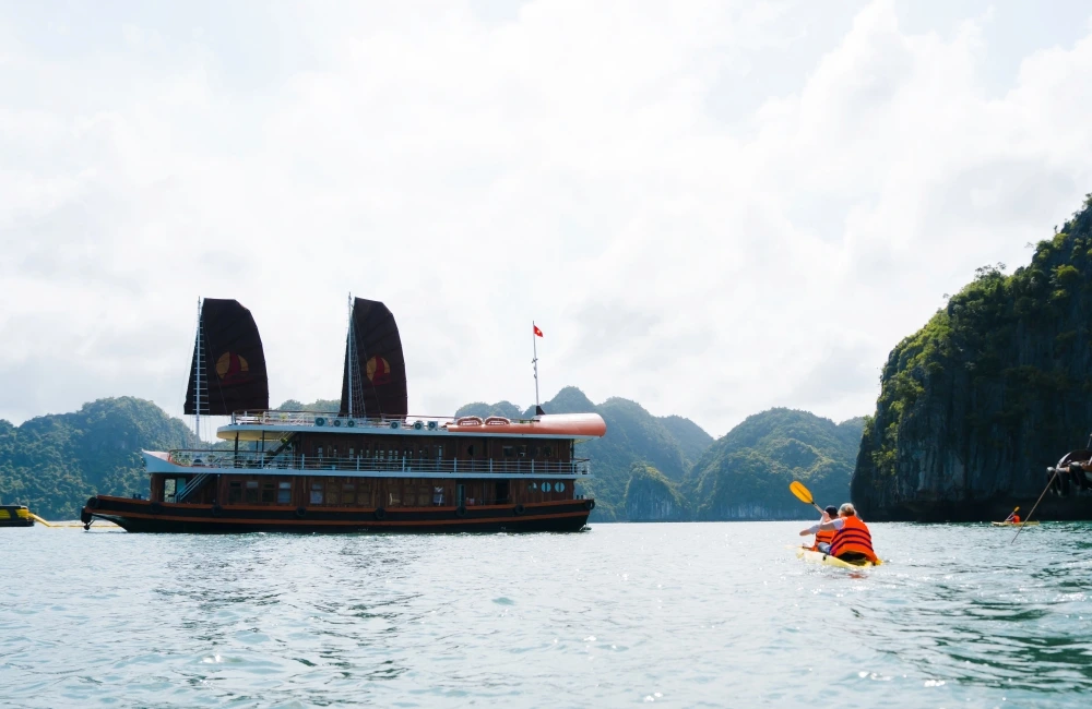 traveler kayaking in Lan Ha Bay with cruise from afar